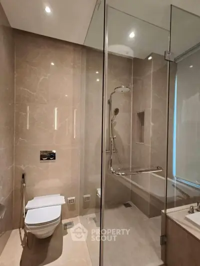 Luxurious modern bathroom with glass shower and elegant marble finishes.