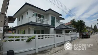 Modern two-story house with white exterior and tiled roof in suburban neighborhood