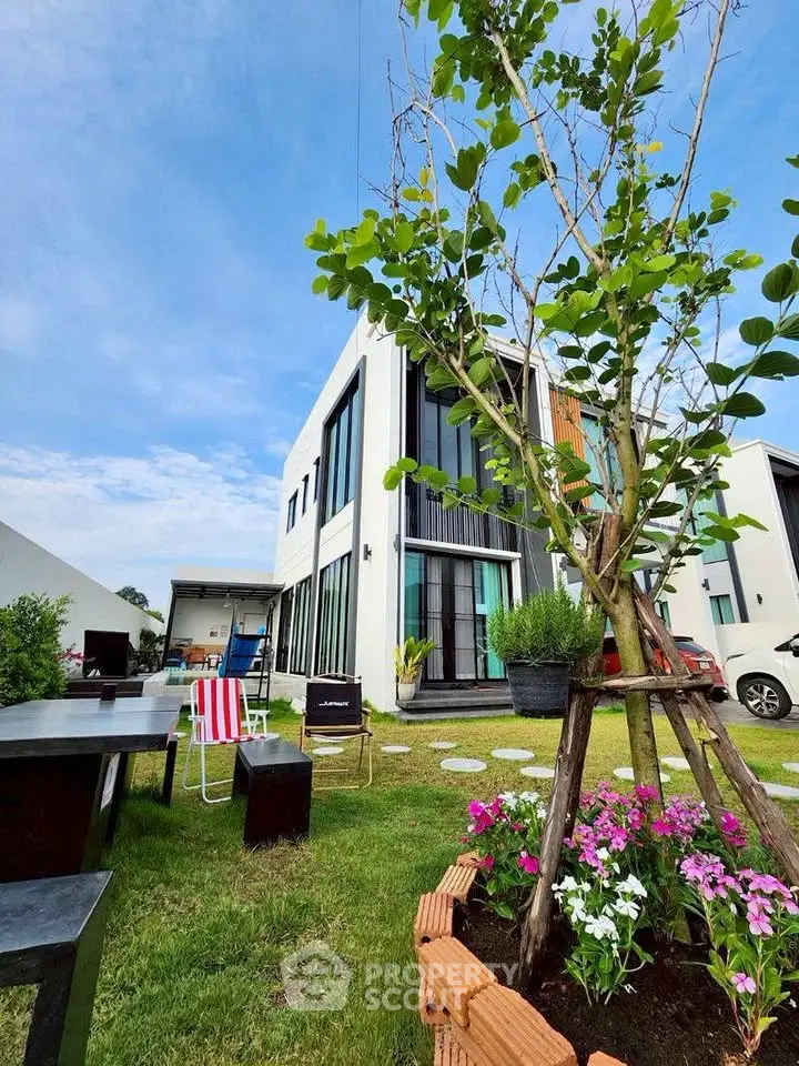 Modern two-story house with lush garden and outdoor seating area, perfect for family gatherings.