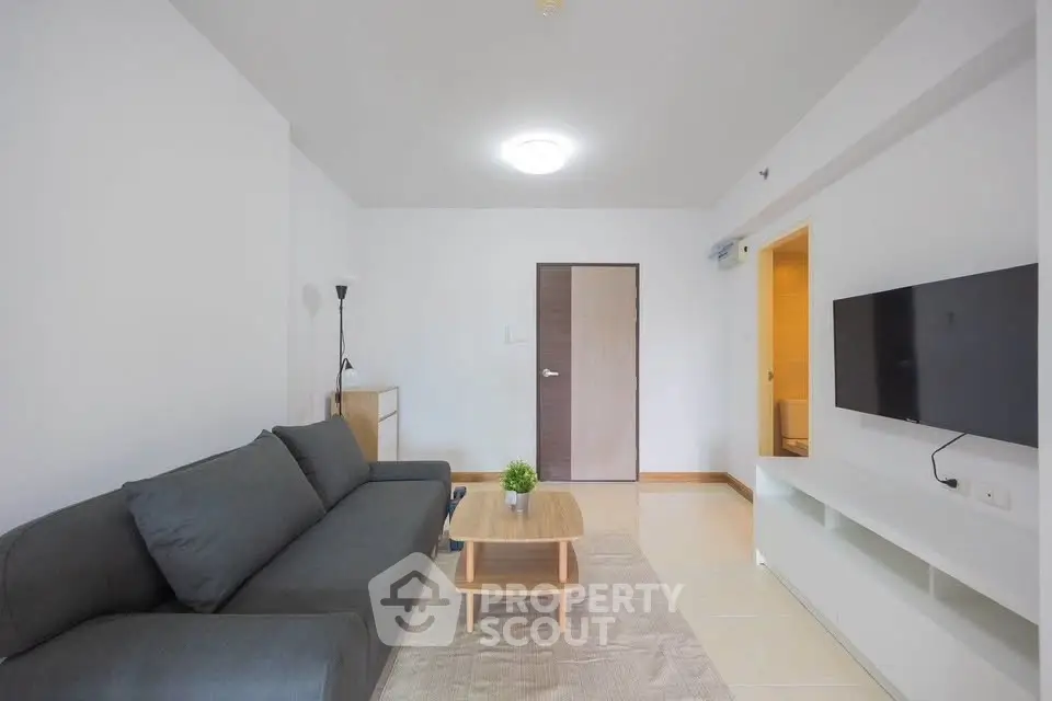 Modern living room with sleek furniture and wall-mounted TV in a minimalist apartment.