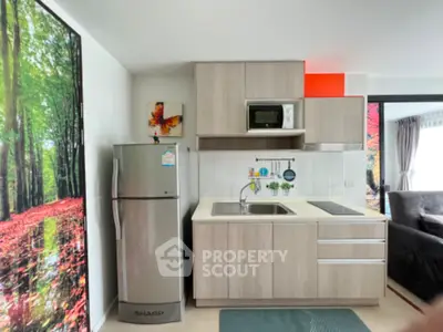Modern kitchen with sleek cabinetry and stainless steel fridge in open layout apartment.