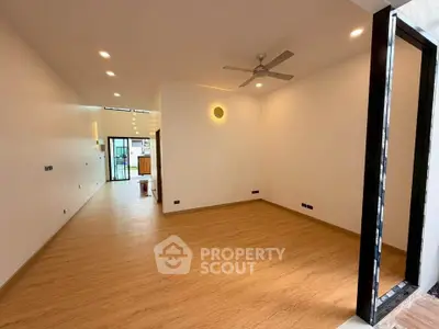 Spacious modern living room with wooden flooring and ceiling fan, ideal for contemporary living.