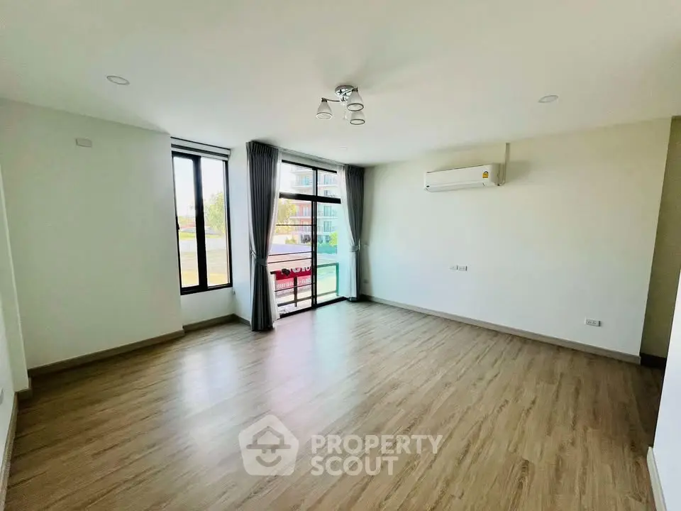 Spacious living room with large windows and modern air conditioning, perfect for natural light and comfort.