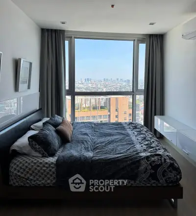 Modern bedroom with large window offering stunning city view, stylish decor, and cozy ambiance.