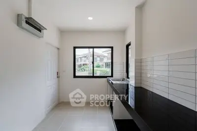 Modern kitchen with sleek black countertops and large windows in a bright, minimalist design.