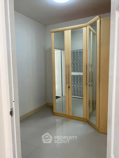Spacious storage room with mirrored wardrobe and sleek tile flooring