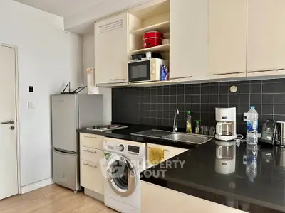 Modern kitchen with sleek black countertops, built-in appliances, and ample storage space.
