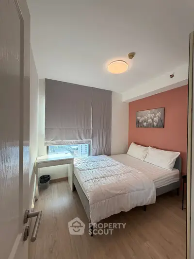 Cozy bedroom with modern decor and city view, featuring a comfortable bed and stylish artwork.