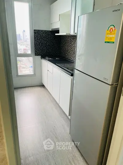 Modern kitchen with sleek design and city view, featuring energy-efficient fridge and stylish backsplash.