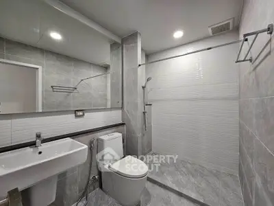 Modern bathroom with sleek fixtures and spacious shower area in contemporary apartment.