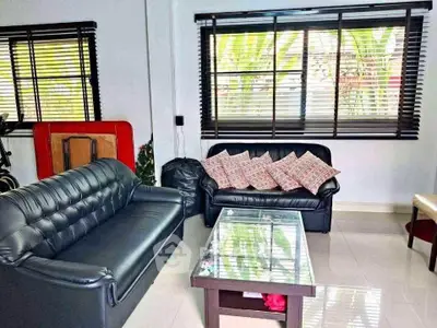 Spacious living room with modern black leather sofas and large windows for natural light.