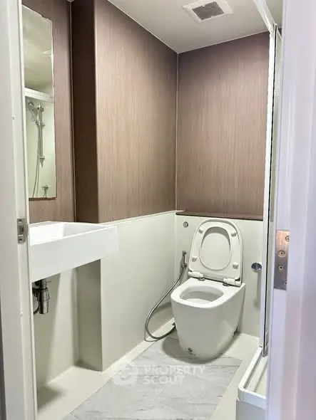 Modern compact bathroom with sleek design and neutral tones, featuring a toilet and sink.