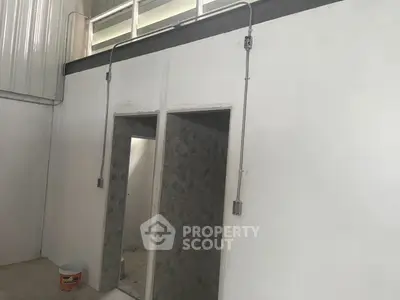 Industrial-style interior with exposed wiring and tiled bathroom entrance, ideal for creative workspace.