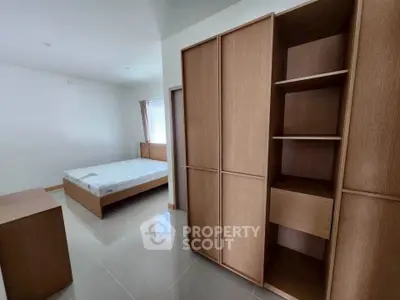 Spacious bedroom with modern wooden furniture and natural light.