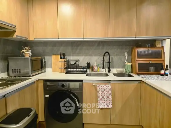 Modern kitchen with wooden cabinets, washing machine, and sleek appliances