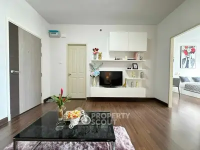 Modern living room with stylish decor and wooden flooring, featuring a sleek TV unit and cozy seating area.