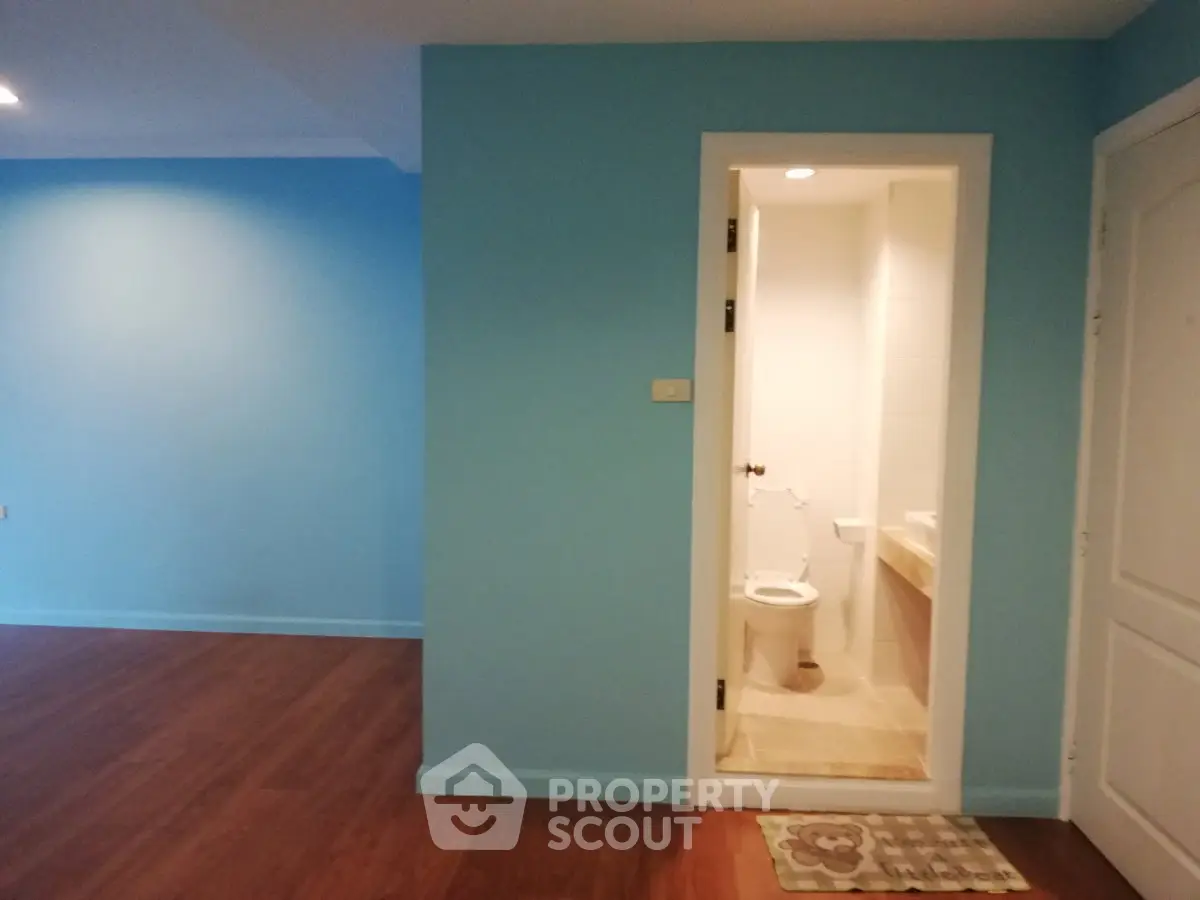 Spacious interior with wooden flooring and a compact bathroom, ideal for modern living.