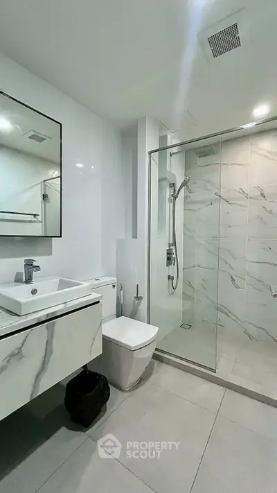 Modern bathroom with sleek design, featuring a glass-enclosed shower and elegant fixtures.