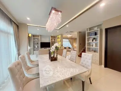 Luxurious open-plan living and dining area with elegant chandelier and marble table.