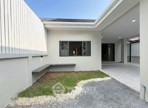 Modern exterior view of a minimalist home with open garage and small garden area.