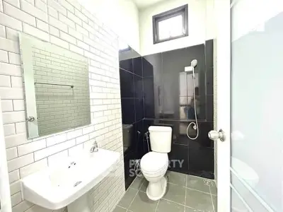 Modern bathroom with sleek black and white tiles, featuring a shower and toilet.