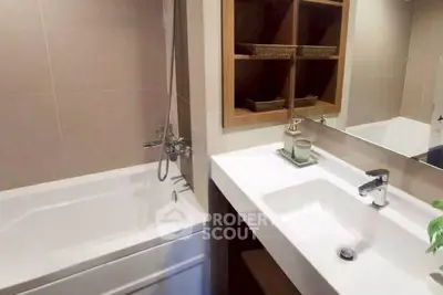Modern bathroom with sleek sink and bathtub, featuring elegant shelving and contemporary design.