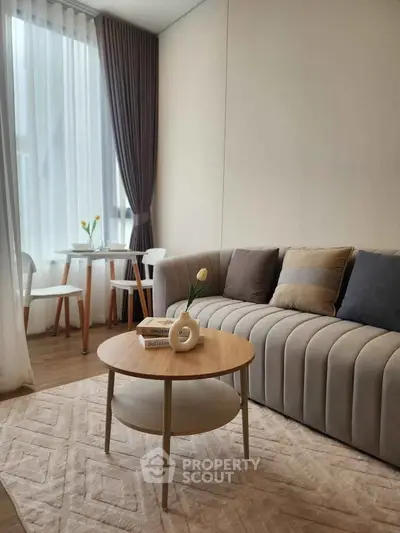 Modern living room with elegant sofa, stylish coffee table, and natural light from large window.