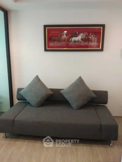 Modern living room with stylish gray sofa and elegant horse painting on the wall.