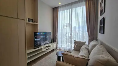 Modern living room with large window and city view, featuring cozy sofa and entertainment center.