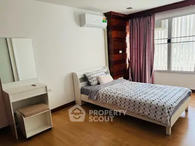 Cozy bedroom with modern decor, featuring a single bed, wooden flooring, and ample natural light.