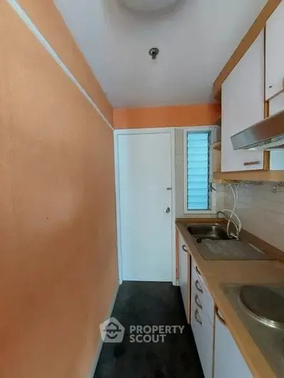 Compact kitchen with orange walls and white cabinets, featuring a closed layout.
