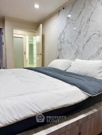 Luxurious bedroom with elegant marble accent wall and cozy bedding