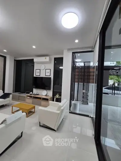 Modern living room with sleek furniture and large windows offering natural light.