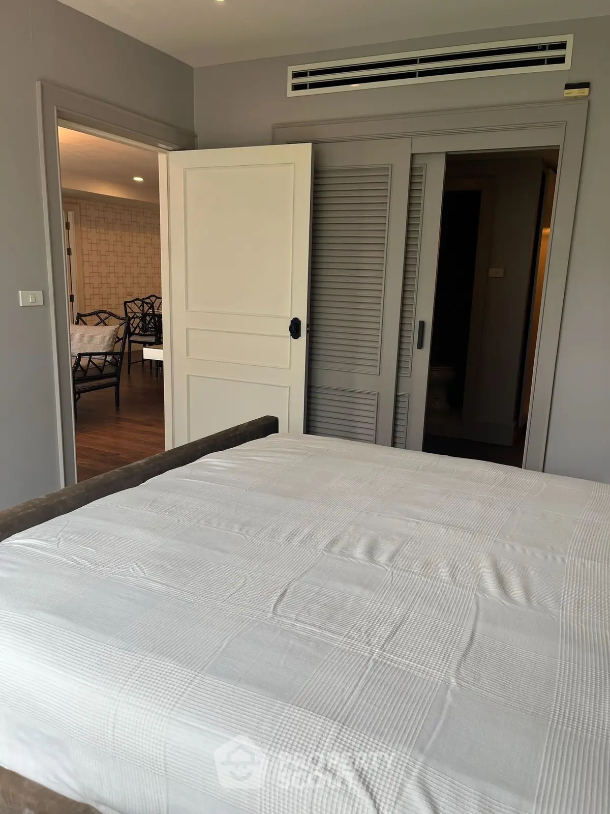 Spacious bedroom with modern design and open door leading to adjacent room.