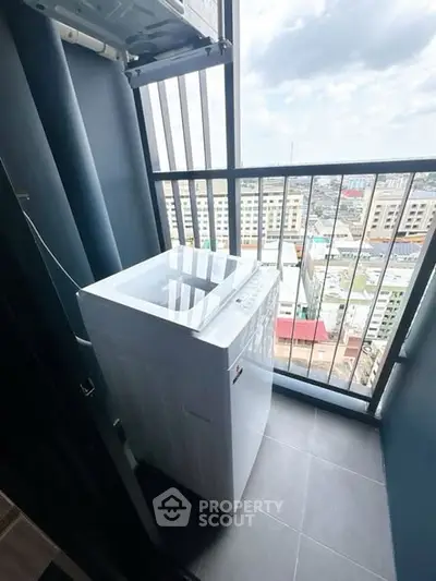 Compact balcony with washing machine and city view, ideal for urban living.