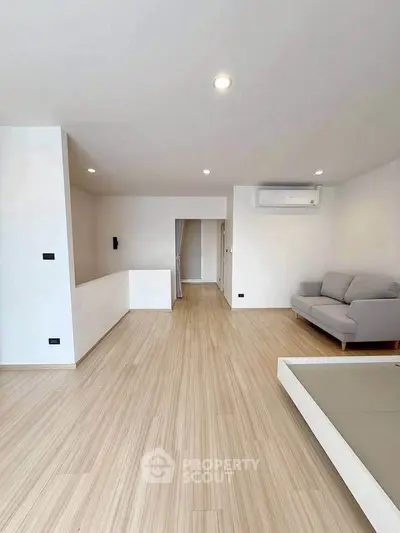 Spacious modern living room with light wood flooring and minimalist decor.