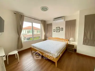 Spacious bedroom with large window and wooden flooring in modern home.