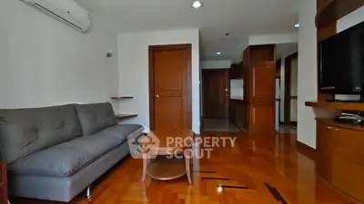 Spacious living room with wooden flooring and modern furniture in a stylish apartment.