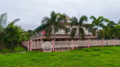 Charming two-story house with lush garden and palm trees, perfect for serene living.