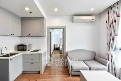 Modern open-plan living room with sleek kitchen and cozy sofa, featuring stylish decor and ample natural light.