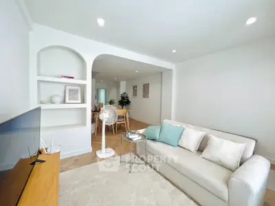 Modern living room with cozy sofa and open dining area, perfect for relaxation and entertaining.