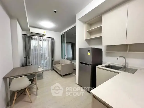 Modern compact apartment with open kitchen and cozy living area, featuring sleek design and natural light.