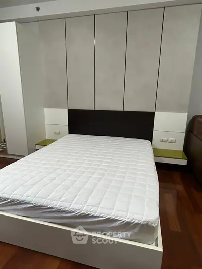 Modern bedroom with sleek design and wooden flooring, featuring a comfortable bed and stylish headboard.
