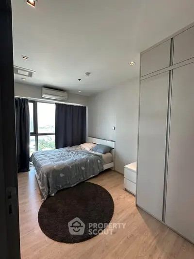 Modern bedroom with large window and stylish decor in high-rise apartment.