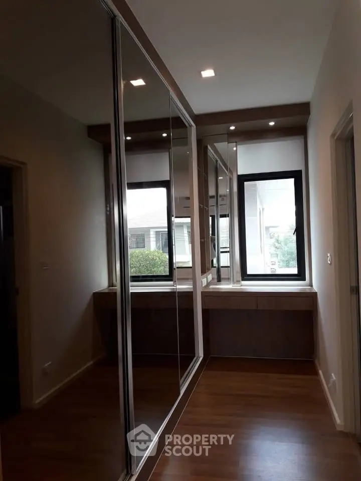 Spacious hallway with mirrored closets and large window for natural light.