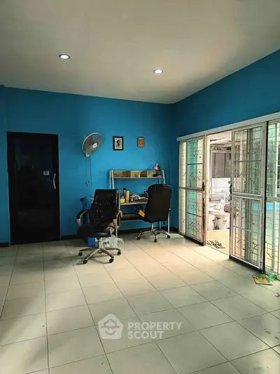 Spacious study room with bright blue walls and large windows for natural light.