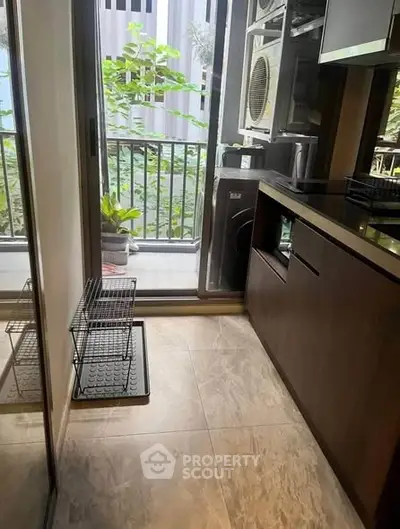 Modern kitchen with balcony view and laundry appliances, featuring sleek cabinetry and tiled flooring.