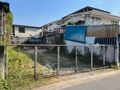 Vacant lot with metal fence in residential neighborhood, ideal for new construction.