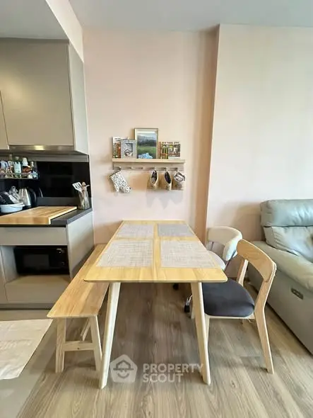 Modern dining area with wooden table and chairs, adjacent to a sleek kitchen setup.