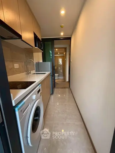 Modern kitchen with sleek appliances and washing machine in compact layout